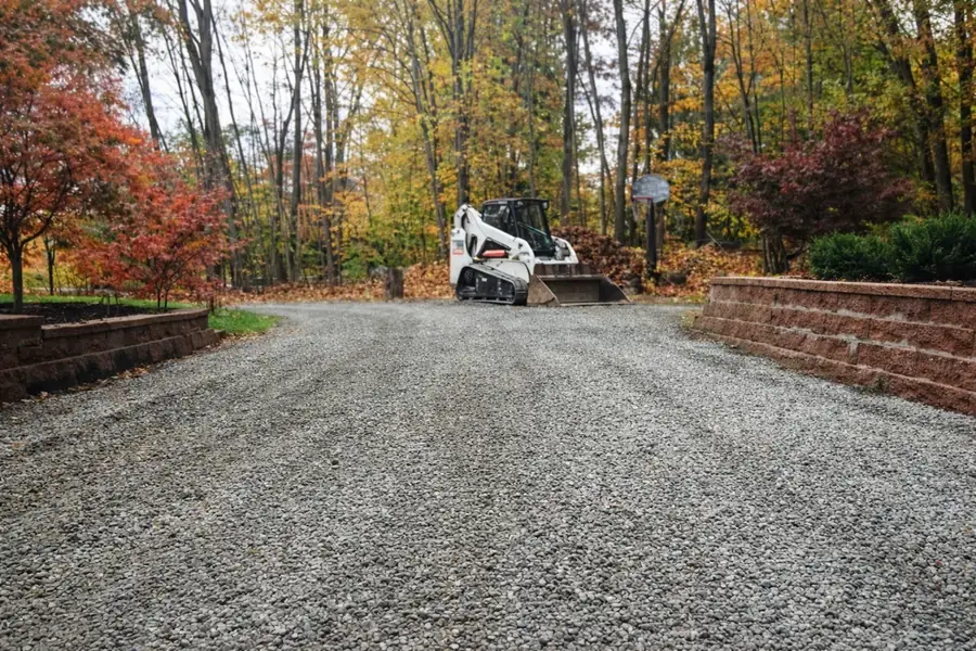 Compact track loader grading a residential stone driveway