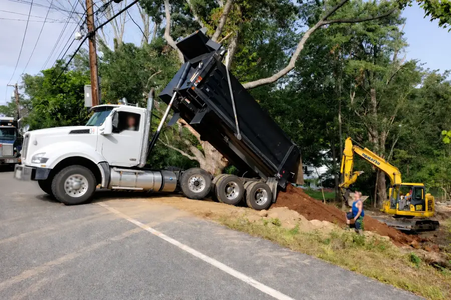 Dump truck placing fill beside an excavator